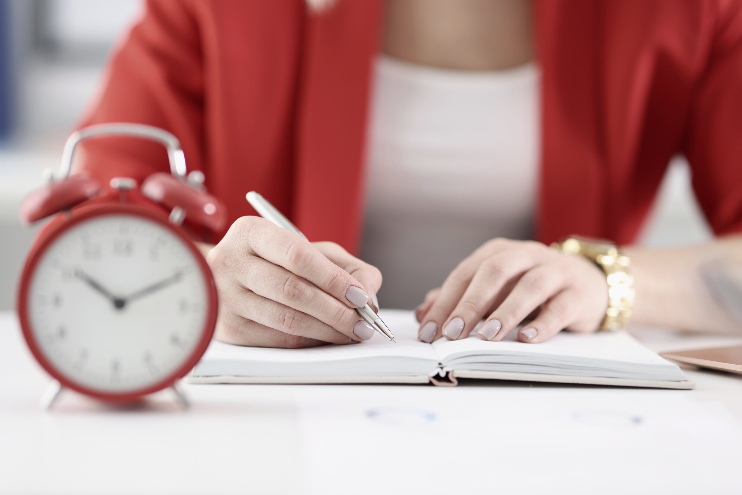 Businesswoman Makes Notes in Documents There Is an Alarm Clock Next to It